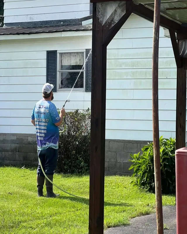 Jones Softwash customer wearing a blue custom work shirt while washing a house