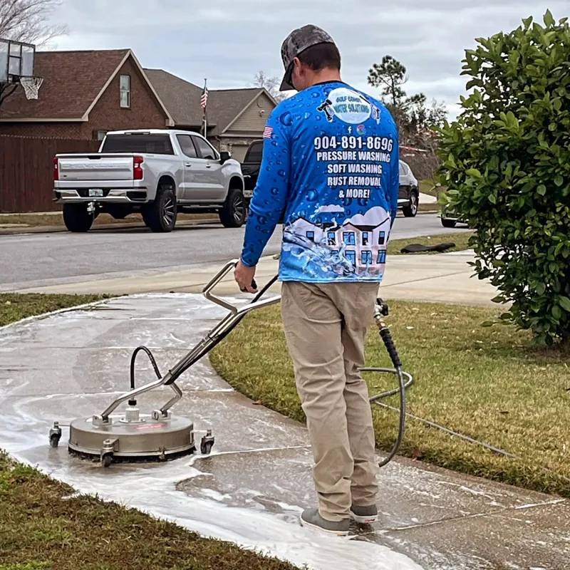 GC Water Solutions customer wearing a custom shirt while pressure washing a driveway